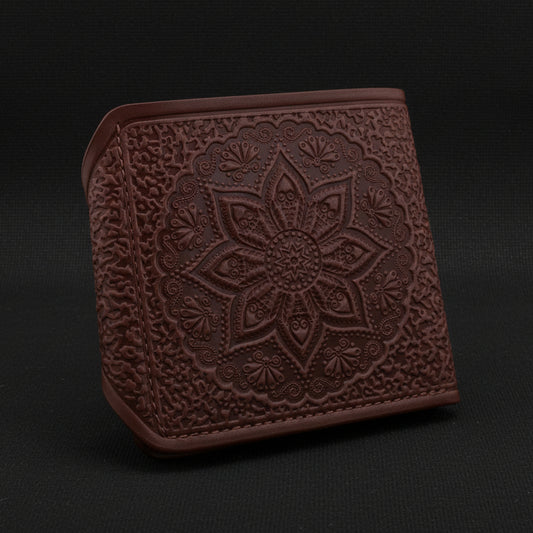 Brown leather wallet with intricate floral embossing on a black background