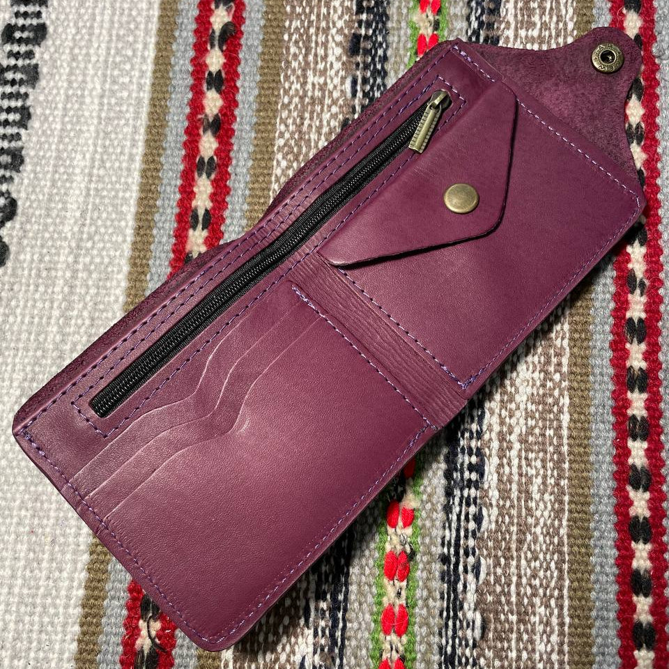 Purple wallet with a zipper on a patterned fabric background