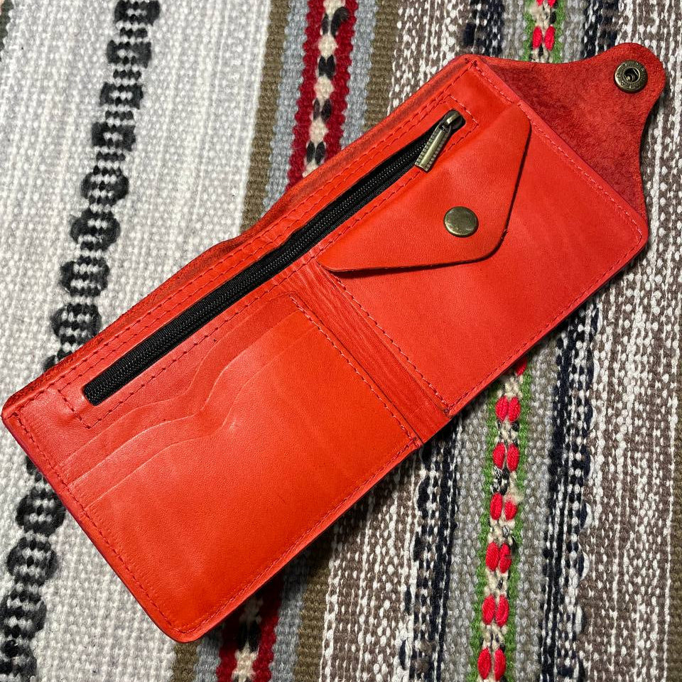 Red leather wallet with a zipper on a patterned fabric background