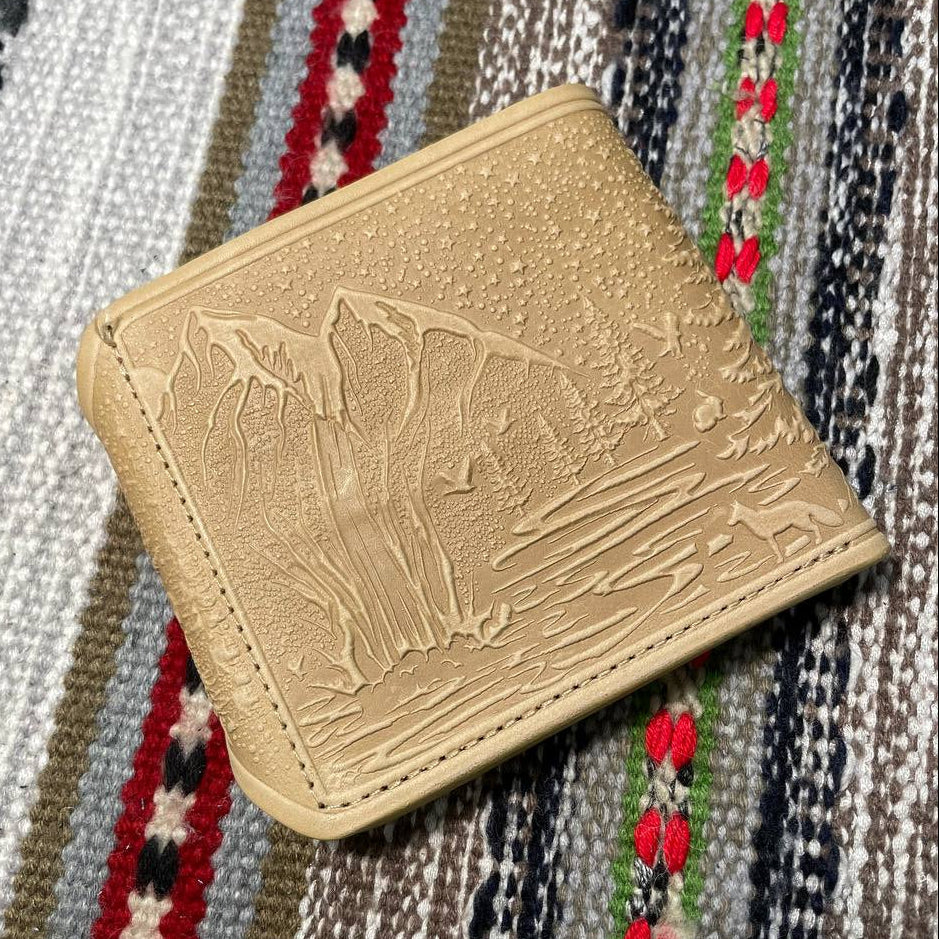 Ivory leather wallet with embossed design on a patterned fabric background