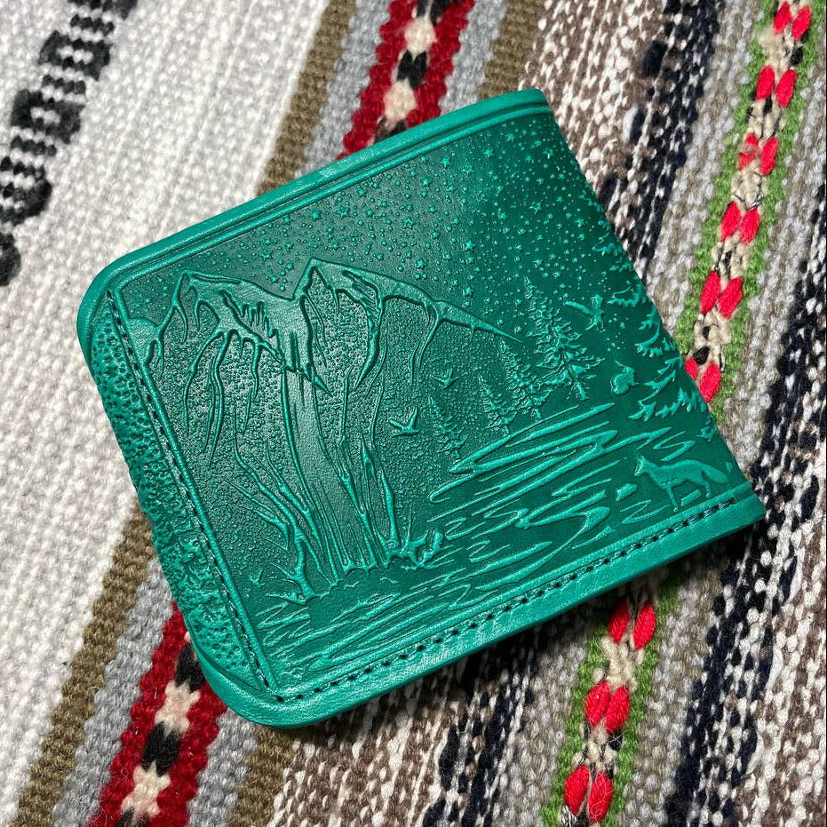 Green textured wallet on a patterned fabric background