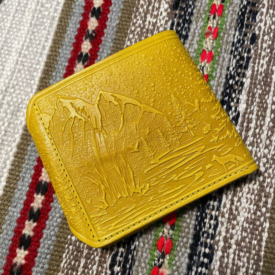 Yellow wallet with embossed design on a patterned fabric background