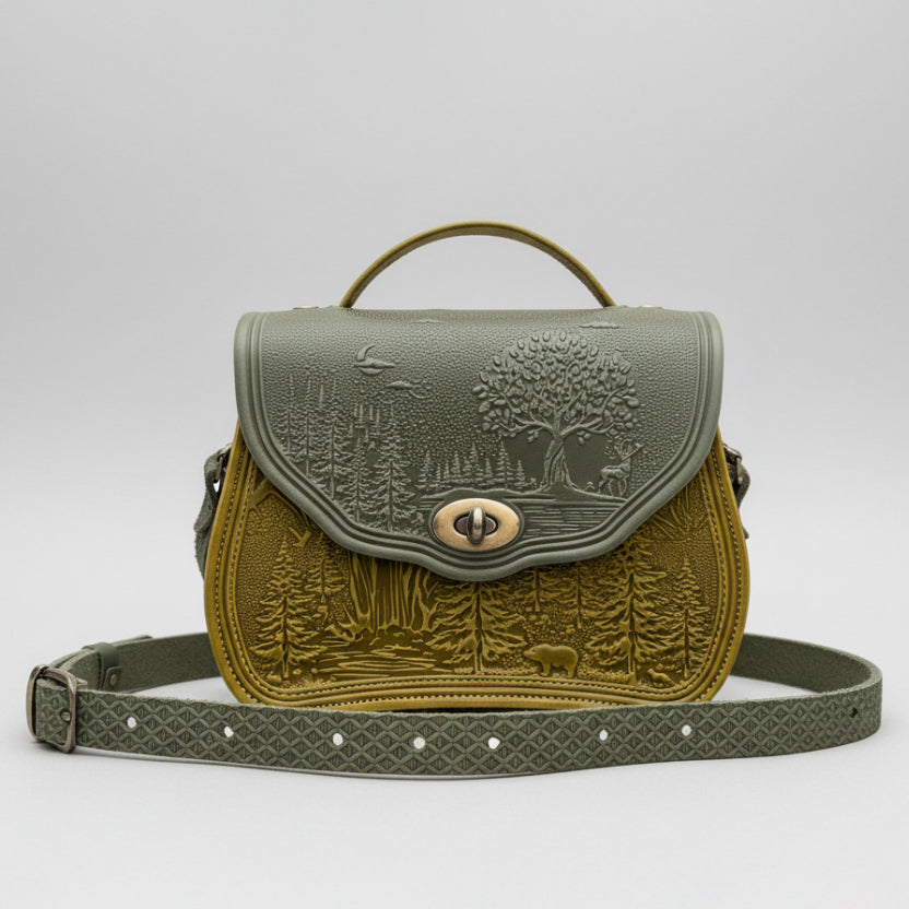 Green leather handbag with nature-themed embossing on a white background