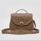 Beige embossed bag on a stone surface with a scenic background