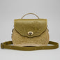 Cognac-ivory textured handbag with a scenic design on a stone surface with a garden background