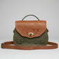 Green and brown embossed handbag on a stone surface with a garden background