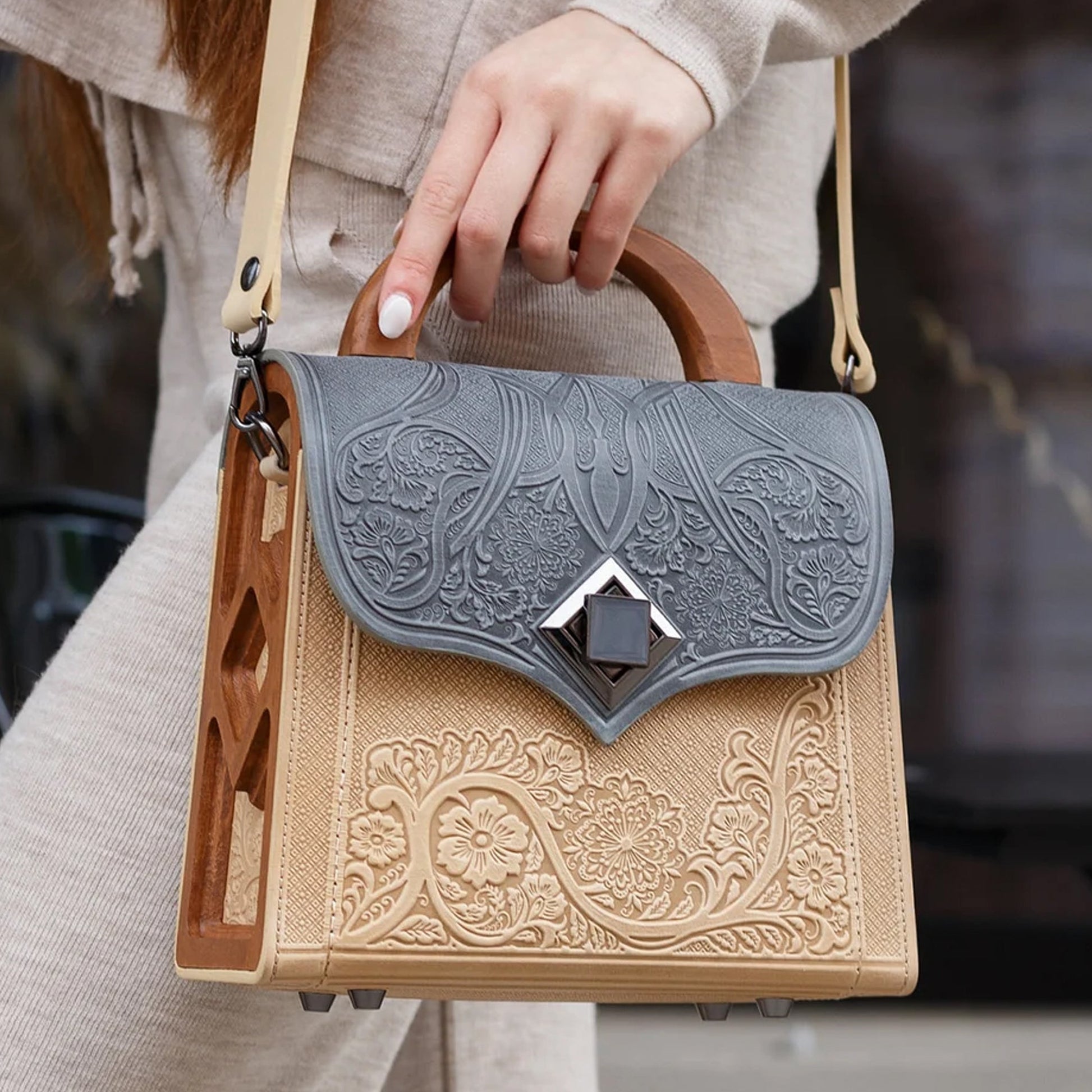 Person holding a decorative handbag with intricate patterns