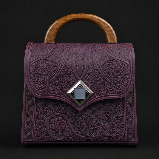Purple embossed handbag with wooden handle on a black background