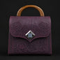 Purple embossed handbag with wooden handle on a black background