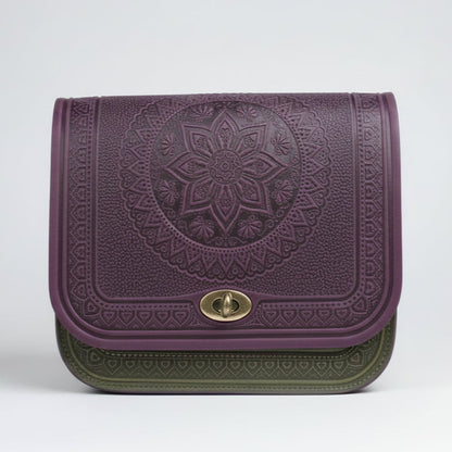 A person wearing a gray checkered coat holding a purple embossed leather crossbody purse with a geometric pattern.