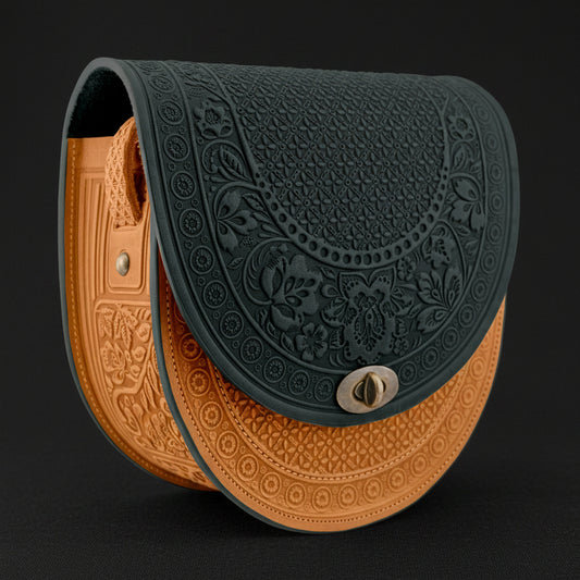 Dark green and cognac leather purse with embossed patterns on a black background