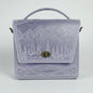 Lavender handbag with mountain design on a white brick wall background