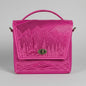 Pink embossed bag with nature design on a white brick wall background