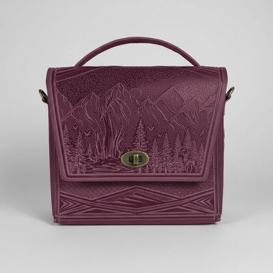 Purple embossed bag with nature design on a white brick wall background