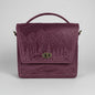 Purple embossed bag with nature design on a white brick wall background
