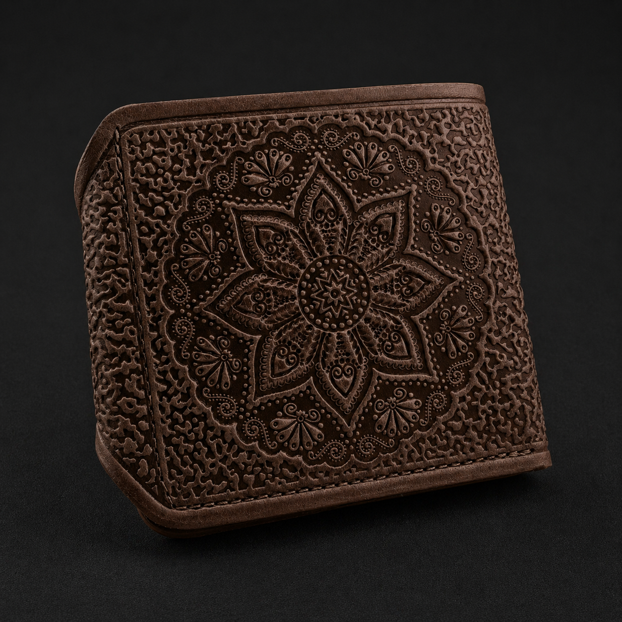 Brown leather wallet with intricate floral embossing on a black background