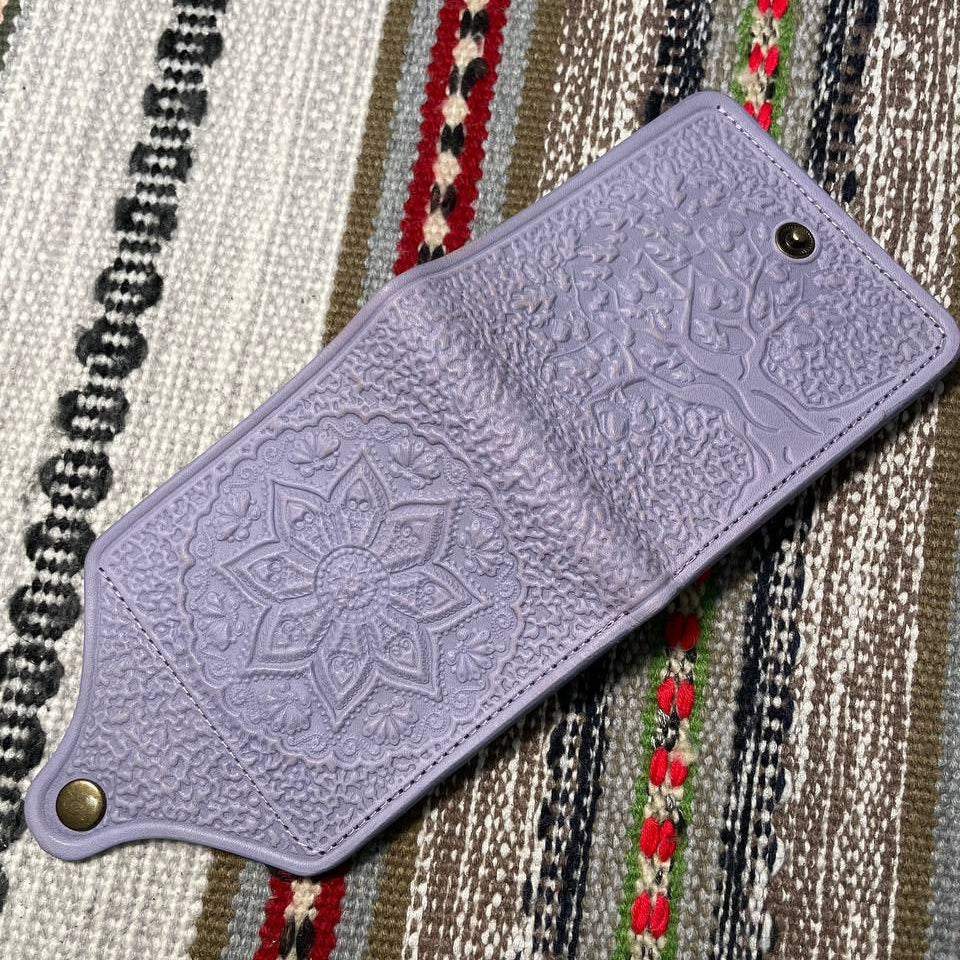 Purple leather phone case with embossed design on a patterned fabric background
