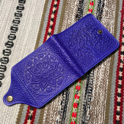 Blue leather wallet with intricate design on a patterned fabric background