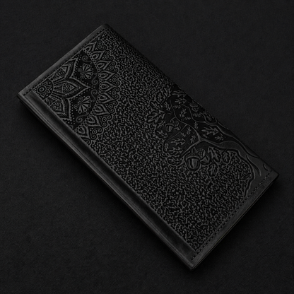 Decorative black leather wallet with embossed tree design on a dark background