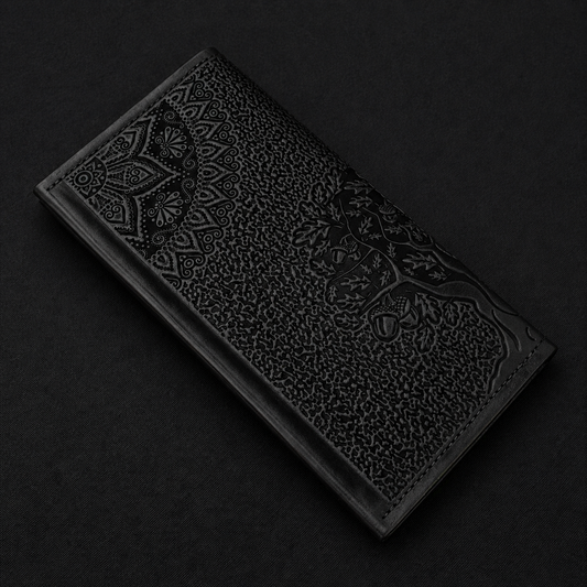 Decorative black leather wallet with embossed tree design on a dark background