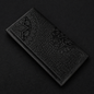 Decorative black leather wallet with embossed tree design on a dark background