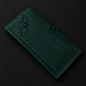Dark green embossed leather wallet on a black background