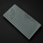 Green leather wallet with intricate patterns on a black background