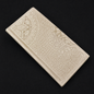 Ivory wallet with embossed patterns on a black background