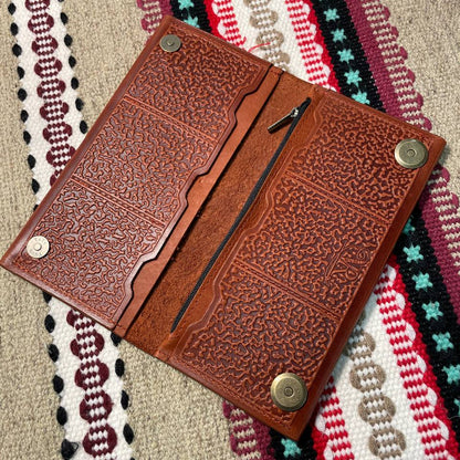 Brown leather wallet with embossed design on a colorful woven fabric background