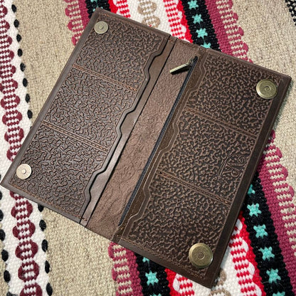Brown leather wallet with embossed design on a colorful woven fabric background