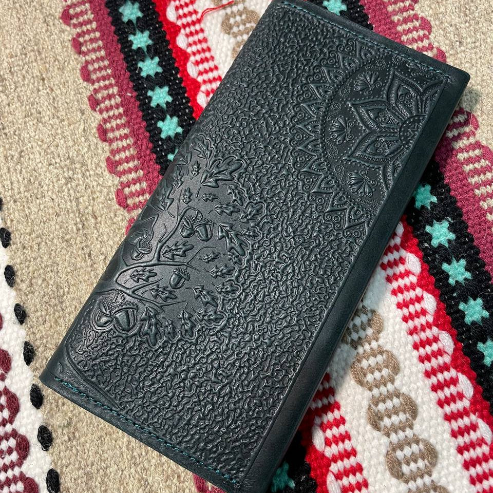 Black embossed wallet on a colorful patterned fabric background