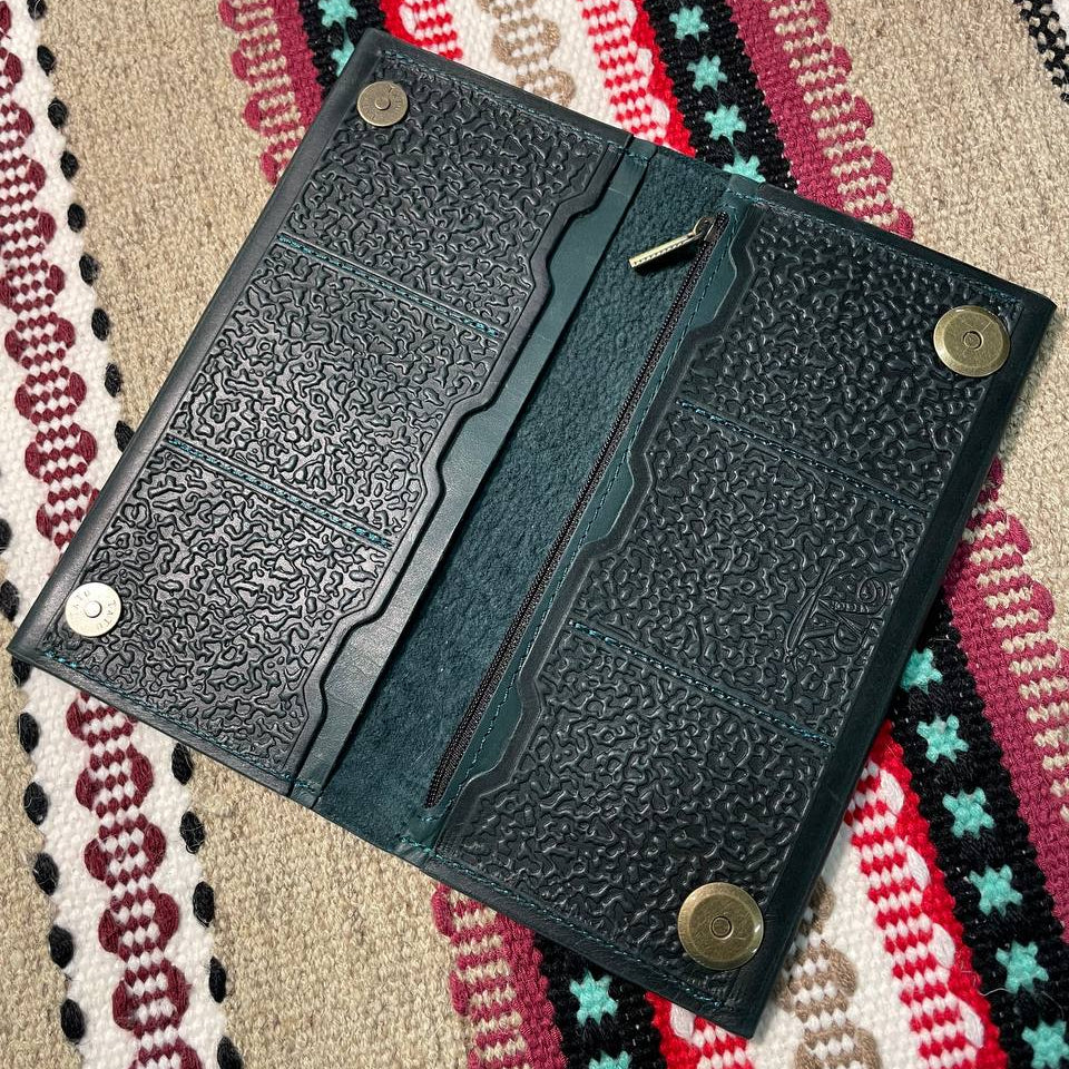 Black leather wallet with embossed design on a patterned fabric background