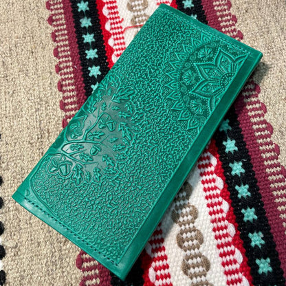 Green embossed wallet on a patterned fabric background