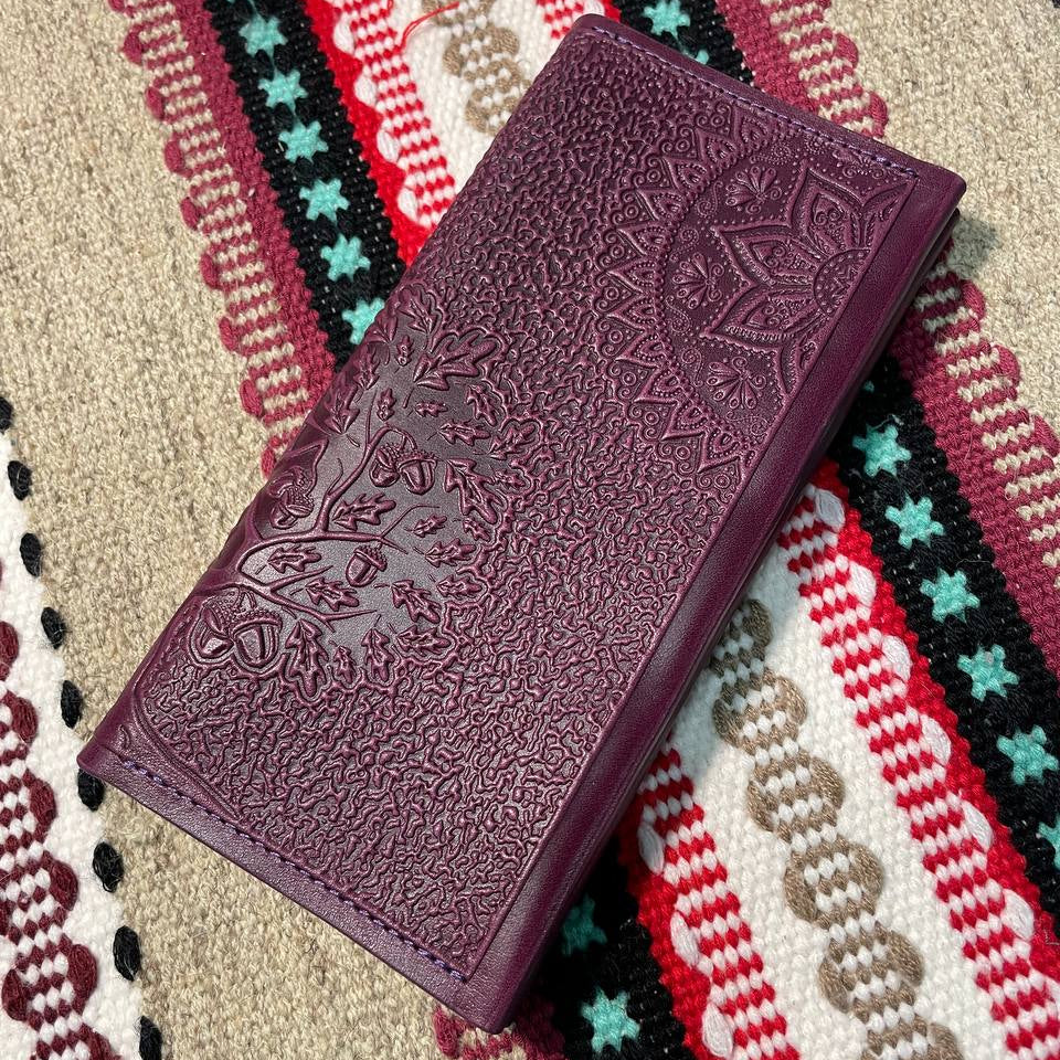 Purple embossed leather wallet on a colorful patterned fabric background