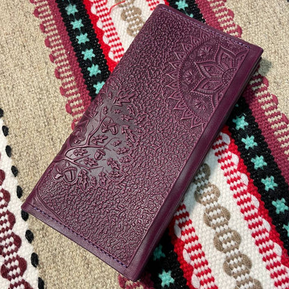 Purple embossed leather wallet on a colorful patterned fabric background