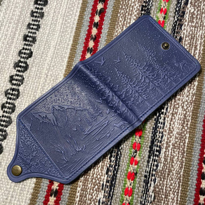 Blue leather wallet with embossed design on a patterned fabric background