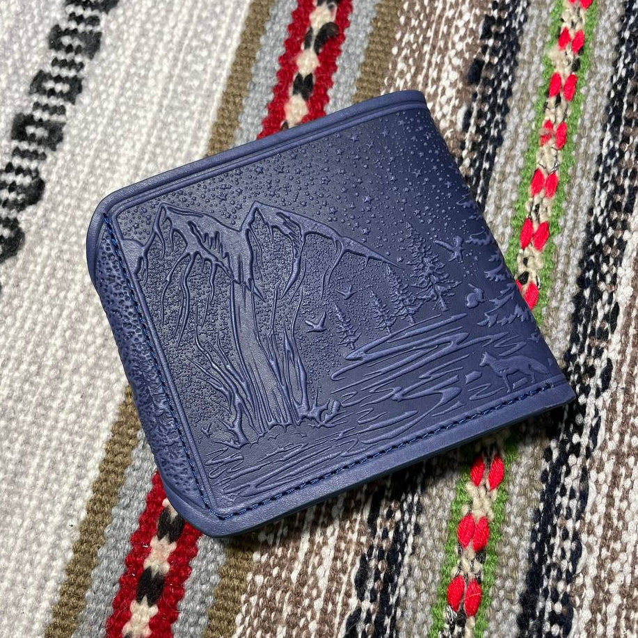 Blue wallet with embossed design on a patterned fabric background