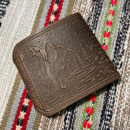 Brown leather wallet with embossed design on a patterned fabric background