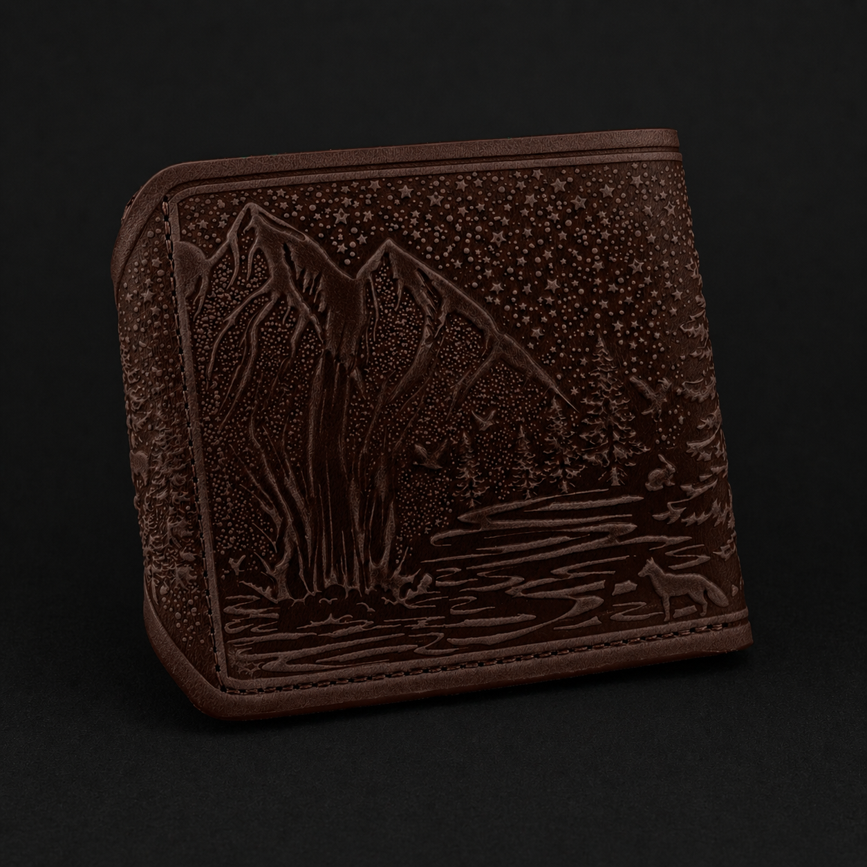 Burgundy leather wallet with embossed mountain design on a black background