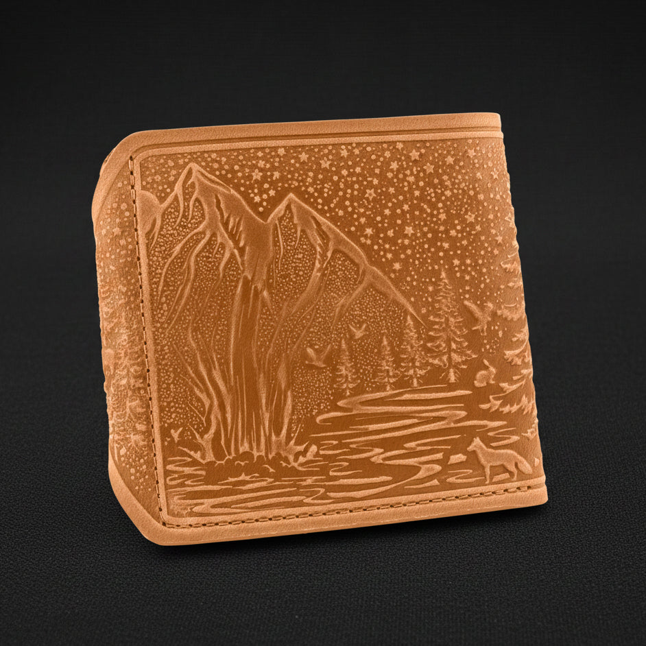 Brown leather wallet with mountain and forest design on a black background
