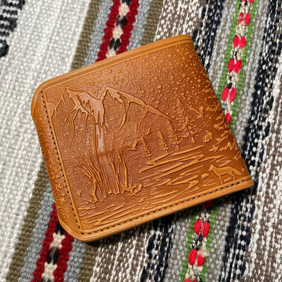 Brown leather wallet with embossed design on a patterned fabric background