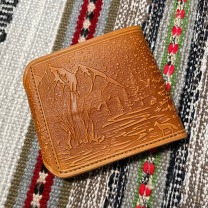 Brown leather wallet with embossed design on a patterned fabric background