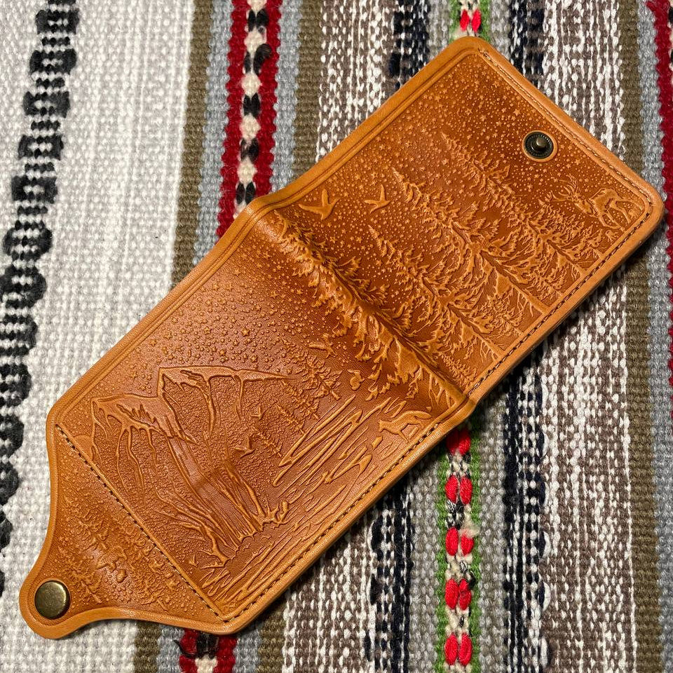 Brown leather wallet with embossed design on a patterned fabric background