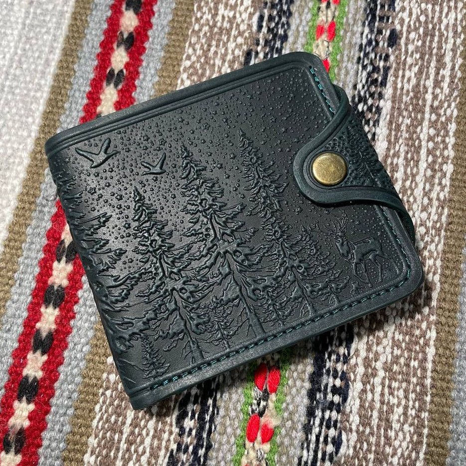 Dark green embossed wallet with nature design on a patterned fabric background
