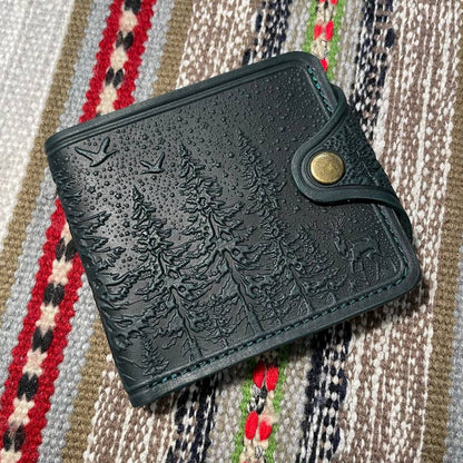Dark green embossed wallet with nature design on a patterned fabric background