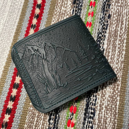 Dark green embossed wallet on a patterned fabric background