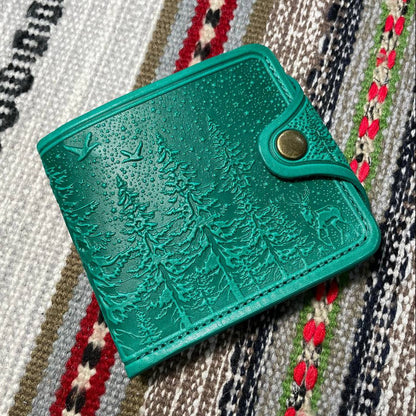 Green textured wallet with a gold clasp on a patterned fabric background