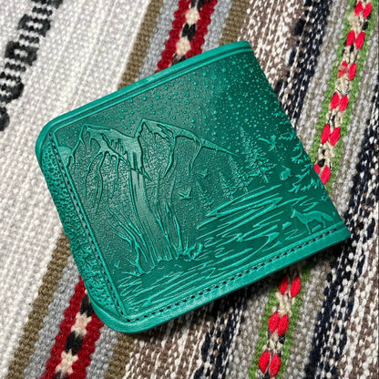 Green textured wallet on a patterned fabric background