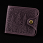 Leather wallet with forest design and gold button on a black background