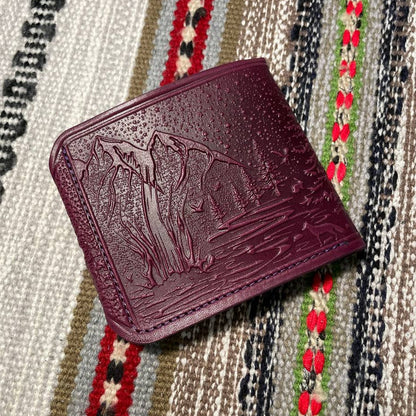 Maroon leather wallet with embossed design on a patterned fabric background